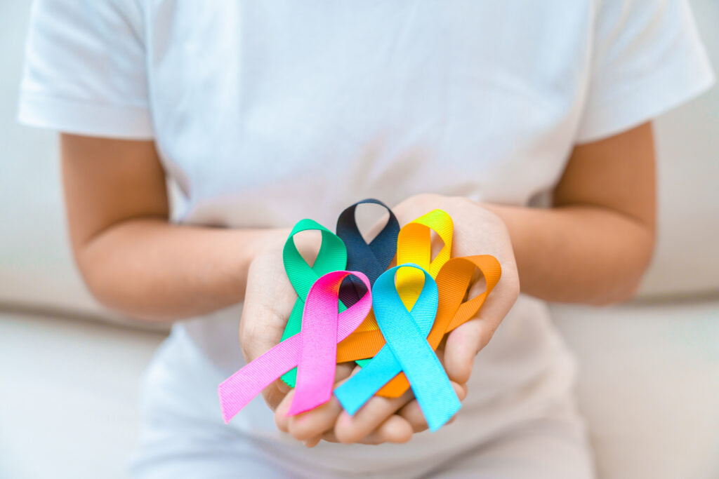 person holding a handful of different colored cancer and disease awareness ribbons